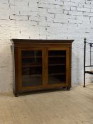 A 19th century bookcase, the twin glazed doors opening to three shelves, raised on later bun