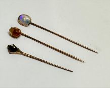 A yellow metal oval mounted water opal stick pin in rub over setting, (1cm x 0.6cm), a yellow