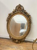 A large gilt composition framed oval wall mirror of 18th century design, with clamshell and scrolled
