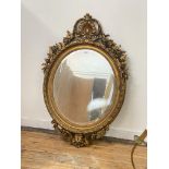 A large gilt composition framed oval wall mirror of 18th century design, with clamshell and scrolled