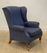 A Georgian style upholstered wingback armchair, turned supports moving on castors. H100cm, W80cm