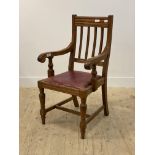 A Victorian oak carver chair, moulded spar back over scrolled open arms, red faux leather