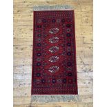 A Super Keshan Bokhara type runner rug, the red field with guls within a border 150cm x 69cm