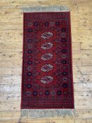 A Super Keshan Bokhara type runner rug, the red field with guls within a border 150cm x 69cm