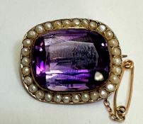 An Edwardian 9ct gold brooch set cushion cut faceted amethyst in rub over mount enclosed within a