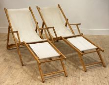 A pair of beech framed folding deck chairs, with white canvas sling seats, paper label inscribed