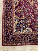 A Persian style rug, the busy red field with medallion and spandrels within a guarded border 363cm x