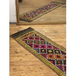 A Suzani kilim runner rug of repeating lozenge design within a running dog border 265cm x 62cm