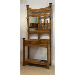 An Arts and Crafts period oak all stand, the openwork back with seven hooks and a bevelled mirror,