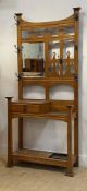 An Arts and Crafts period oak all stand, the openwork back with seven hooks and a bevelled mirror,