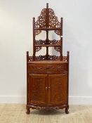 A Chinese hardwood corner etagere, with two open shelves having profusely pierce carved fret panels,