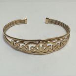 A 9ct gold interlocking Celtic knot open work expanding bangle of tapering design with plain