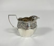 An Edwardian Birmingham silver milk jug with s shaped handle and gadroon scalloped top and chased
