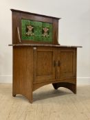 An Arts and Crafts period oak wash stand, the tile back over rouge marble top and two panelled