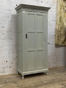 A green painted hardwood hall cupboard, with blind fret frieze over panelled door enclosing interior