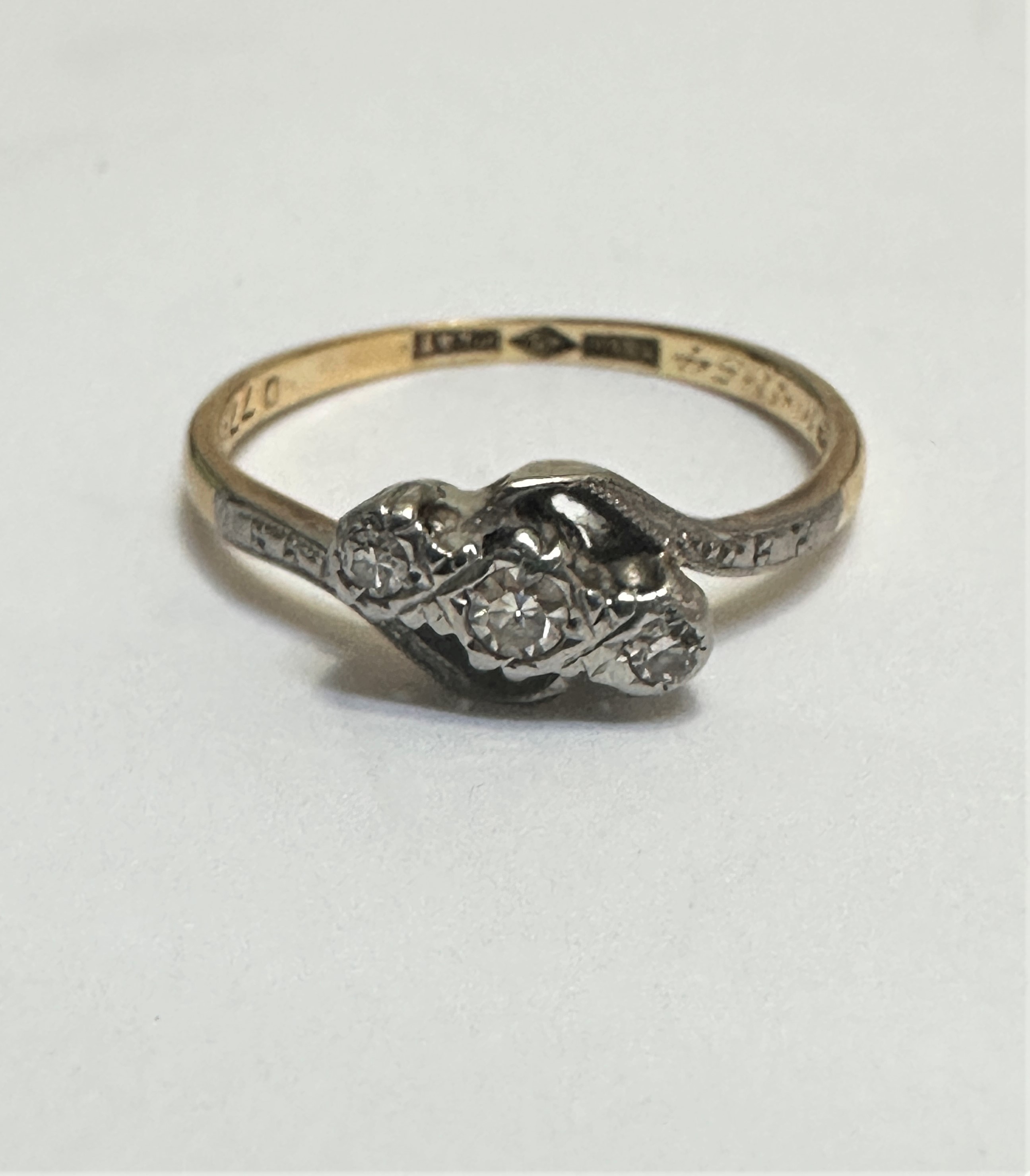An 18ct gold and platinum mounted three stone diamond cross over ring mounted in rub over
