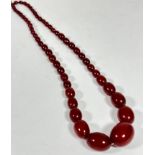 A dark amber 1920's graduated bead necklace, (L x 30cm) largest bead, 3cm. 51.4g