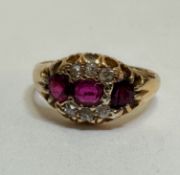An 18ct gold three stone ruby and diamond ring, the oval cut stone flanked by a circular circular