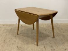 A mid century oak drop leaf dining table by Priory, in the Ercol style, the circular top raised on