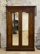 An Edwardian walnut double wardrobe, the projecting cornice over floral carved frieze and twin
