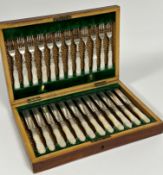 An Edwardian mahogany canteen containing twelve pairs of engraved Epns fruit knives and forks.