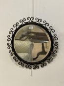 A wrought metal circular wall hanging mirror, the frame with conforming C scrolls enclosing a