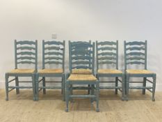 A set of six blue painted ladder back dining chairs with rush seats raised on turned supports