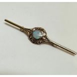 A 9ct gold bar brooch set circular water opal in rub over setting enclosed within a open scroll