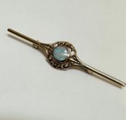 A 9ct gold bar brooch set circular water opal in rub over setting enclosed within a open scroll