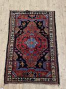 A hand knotted Persian Hamadan design rug, with a dark abrashed field and bordered 127cm x 84cm