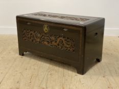 A Chinese style carved camphor wood chest, the lid opening to a plain interior, raised on bracket