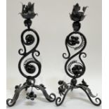 A pair of iron candlestick holders with acanthus leaf design on a scrolling stem and tripod base (h-