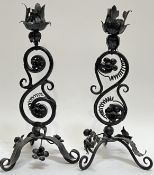 A pair of iron candlestick holders with acanthus leaf design on a scrolling stem and tripod base (h-