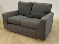 A contemporary two seat sofa, upholstered in grey fabric, raised on beech block supports H74cm,
