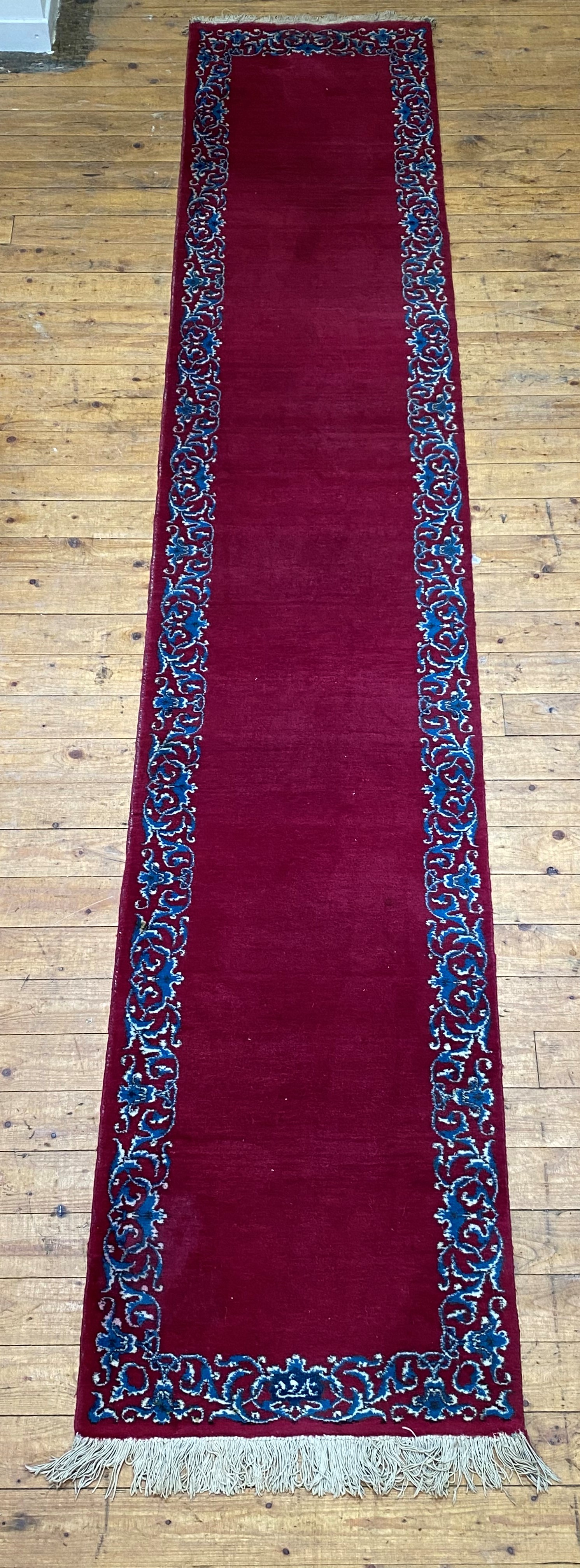A Persian Kashan design runner rug, the red field with signature to the meandering floral border