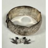 A Sterling silver large stiff hinged cuff style bangle with all over engraved scroll design complete