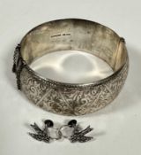 A Sterling silver large stiff hinged cuff style bangle with all over engraved scroll design complete