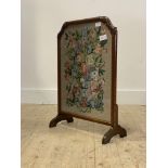 An early 20th century walnut fire screen with embroidered panel worked in a floral design, H68cm