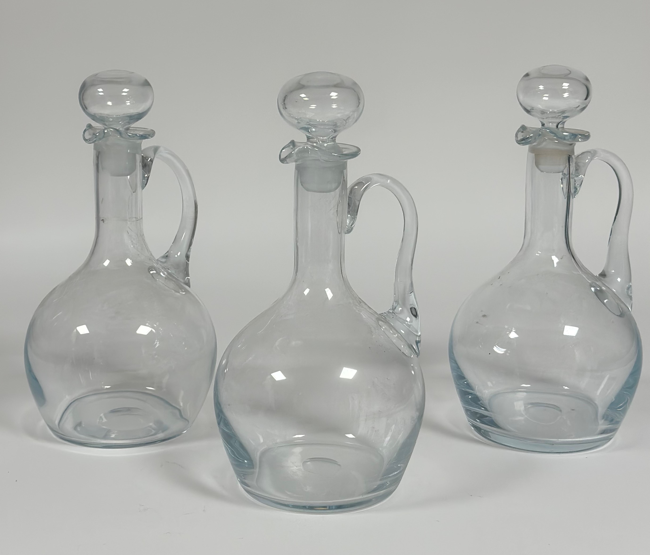 A group of three wine decanters each with c-scroll handles and stoppers (tallest h- 34cm)(no chips