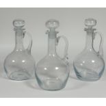 A group of three wine decanters each with c-scroll handles and stoppers (tallest h- 34cm)(no chips