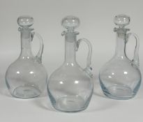 A group of three wine decanters each with c-scroll handles and stoppers (tallest h- 34cm)(no chips