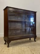 A mahogany bookcase, with two drawers over two glazed doors enclosing two shelves, raised on