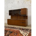 A 1970s mid century teak wall display unit, the floating superstructure with smoked glass cabinets