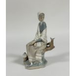 A Lladro figure of a Shepard lady sitting on a trunk looking at a bird. (h- 25.5cm) (no signs of