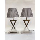 A pair of Contemporary chrome plated table lamps of crossed form, complete with pleated shades