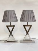 A pair of Contemporary chrome plated table lamps of crossed form, complete with pleated shades
