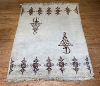 A hand knotted Moroccan rug, the ivory field decorated with a motif representing a traditional