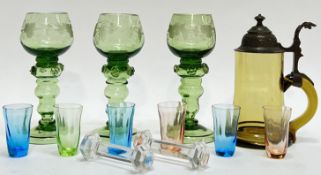 A mixed group of coloured glass comprising three green engraved blown glass stemmed cups/goblets (h-