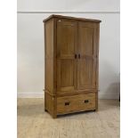 An oak two door wardrobe with interior fitted for hanging, over a drawer to base H147cm, W109cm,