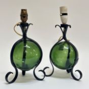 A pair of arts and crafts style green blown glass with wrought iron decoration and raised on a three